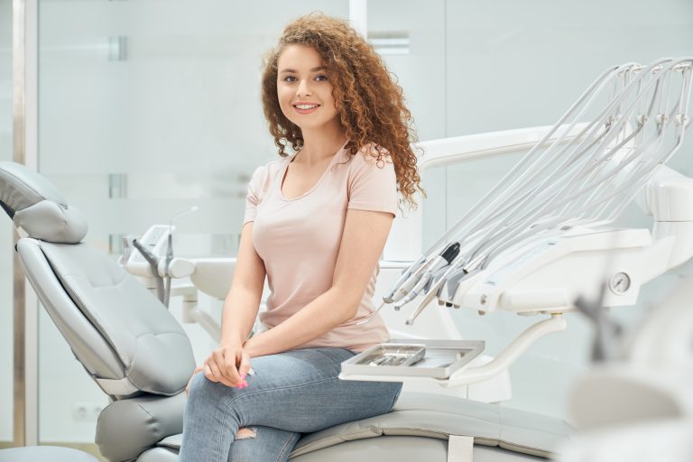 smiling girl with curly hair sitting in dental chair